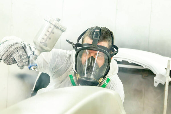 Услуги по окрашиванию автомобилей: Маляры мужского пола, владеющие навыками использования автомобильных распылителей краски в масках для предотвращения диспергирования распылительной краски в закрытой кабинке для работы со здоровьем и качеством.