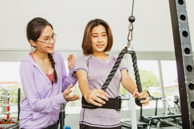 Kadın kişisel antrenör, sağlık ekipmanlarını önemseyen tombul kadınlara danışmanlık öneriyor. Halat egzersizleri, kol kasları, üst kol kasları..