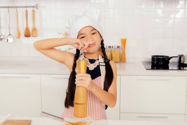 Küçük tatlı Asyalı aşçı öğrenci aşçı mutfakta lezzetli yemekler yapmayı öğreniyor. Bir yumurta kasesinde baharat ve biber hazırlayın: Aşçılık ve beslenme öğrenme okulunda konseptler.