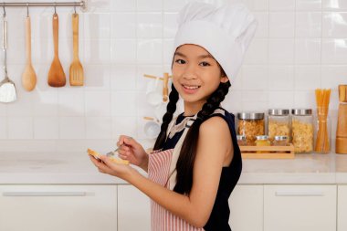 Küçük tatlı Asyalı aşçı öğrenci aşçı mutfakta lezzetli yemekler yapmayı öğreniyor. Bir yumurta kasesinde baharat ve biber hazırlayın: Aşçılık ve beslenme öğrenme okulunda konseptler.