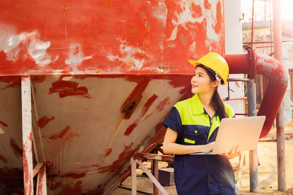 stock image Female technician holding laptop inspects wastewater treatment station industrial plant large steel tank separating liquid waste sewage sludge draining effluent into wastewater treatment plant.