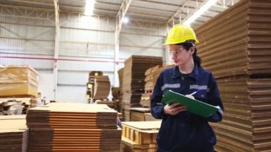 Portre işçisi profesyonel güzel kadın depo çalışanı depodaki malları kontrol ediyor karton imalat fabrikası ürünleri paketliyor lojistik çalışmaları not alıyor.. 