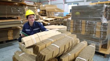 Portre işçisi profesyonel güzel kadın depo çalışanı depodaki malları kontrol ediyor karton imalat fabrikası ürünleri paketliyor lojistik çalışmaları not alıyor.. 