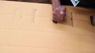 Erkek işçi, kağıt paketleme endüstrisinde paketlemek için karton kutularda delikler açmak için özel bir araç kullanır..