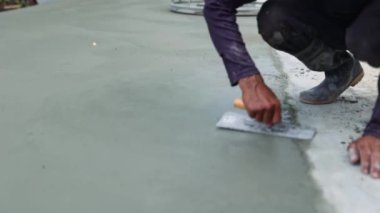 Kıdemli inşaat işçisi, kurutulmamış beton yüzeyi süslemek için sıva malzemesi kullanıyor ve parlayan helikopterle birlikte pürüzsüz ve dayanıklı hale getiriyor: saha çalışması.