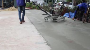 Erkek inşaat işçisi profesyonel inşaat alanında çalışıyor. Yüzeyi pürüzsüz ve dayanıklı hale getirmek için henüz kurumamışken beton yüzeyini temizlemek için helikopter kullanıyor..