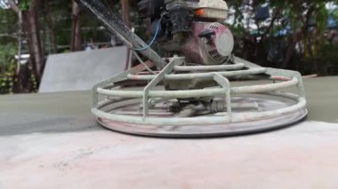 Erkek inşaat işçisi profesyonel inşaat alanında çalışıyor. Yüzeyi pürüzsüz ve dayanıklı hale getirmek için henüz kurumamışken beton yüzeyini temizlemek için helikopter kullanıyor..