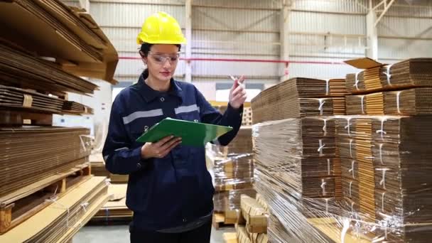 肖像労働者専門の若い美しい女性の倉庫労働者は倉庫のボール紙の製造工場プロダクト包装のロジスティクスクリップボードでノートを取ることを点検します — ストック動画