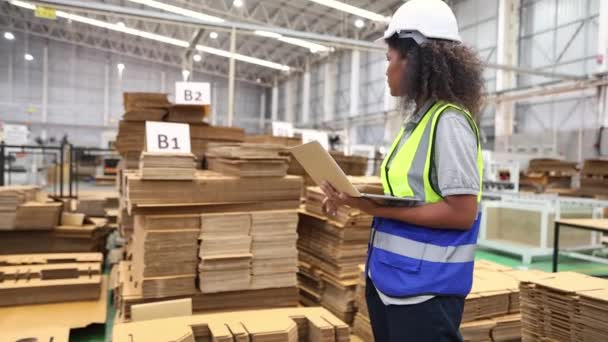 非洲裔美国女工站在托盘架上检查一堆纸板纸板厂包装产品物流在笔记本电脑上工作记录数据 — 图库视频影像