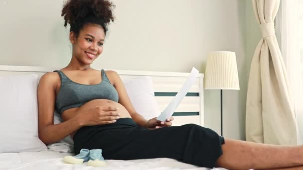 Glad Porträtt Gravid Afroamerikansk Mor Sitter Försiktigt Gnugga Magen Sängen — Stockvideo