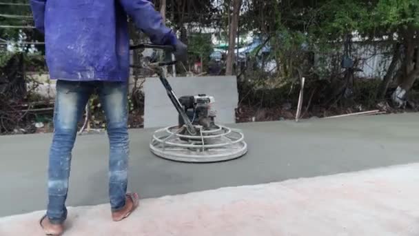 男性の建設作業員の専門家は 表面を滑らかで耐久にするためにまだ乾燥していないときにセメントコンクリートの表面をスクラブするためにコピーを使用して建設現場で屋外で動作します — ストック動画
