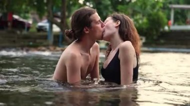 Mutlu romantik çift yaz tatillerinde doğada geziyor ve mutlu bir tatil köyünde kalıyor derede su içip öpüşüyor ve birbirlerine sarılıyorlar..