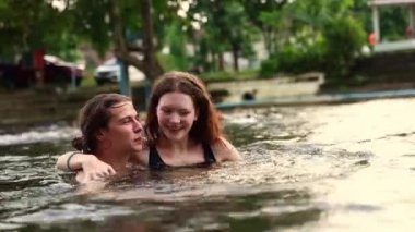 Mutlu romantik çift özel bir tatile çıkıyor yaz tatilinde mutlu bir tatil köyünde kalıyor derenin serin sularında oynuyor ayakta duruyor ve birbirlerine sarılıyorlar..