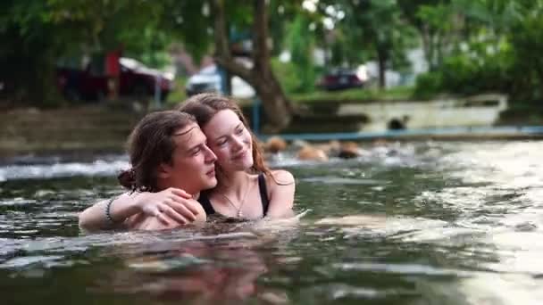 快乐浪漫的夫妻在大自然的夏天旅行 呆在一个快乐的度假胜地 在清凉的河里玩耍 站在那里拥抱对方 彼此是最快乐的 — 图库视频影像