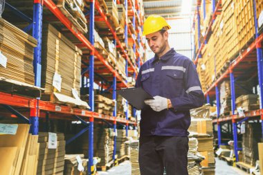 Beyaz adam, karton kutu deposunda profesyonel servis görevlisi, ihracat lojistik fabrikası devriye gezerken kayıt paketlerini kontrol ediyor..