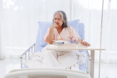 Yaşlı Asyalı kadın, mide iltihabı, gastrointestinal hastalık, hastaneye yatırılmış, tatsız lapa yemekten yorulmuş, iştahı yok. Yemek istemiyorum, kendimi toparlamaktan yoruldum..