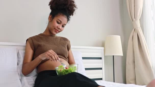 アフリカ系の若い母親は ビタミンやミネラルで健康的なサラダを食べています 妊娠中の女性に有益な野菜と胎児の健康免疫を高めるために栄養を追加する — ストック動画