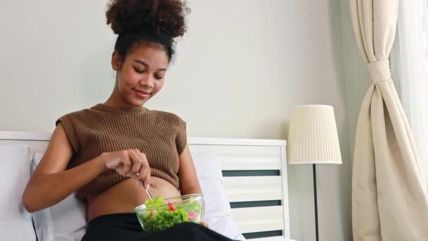 アフリカ系の若い母親は ビタミンやミネラルで健康的なサラダを食べています 妊娠中の女性に有益な野菜と胎児の健康免疫を高めるために栄養を追加する — ストック動画