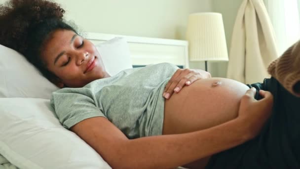 幸せな肖像画妊娠したアフリカ系アメリカ人の母親はベッドに横たわり 妊娠中の赤ちゃんを優しく愛し 健康な発達胎児を見ることを楽しみにしています — ストック動画