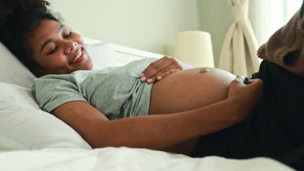 幸せな肖像画妊娠したアフリカ系アメリカ人の母親はベッドに横たわり 妊娠中の赤ちゃんを優しく愛し 健康な発達胎児を見ることを楽しみにしています — ストック動画