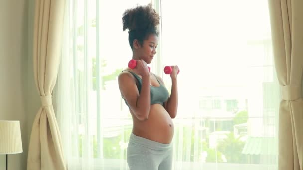 美国美丽的非洲母亲怀孕了 为了健康地照顾自己的健康 她在卧室里做运动 把哑铃上下提起 慢慢地扭动手臂肌肉 然后分娩 — 图库视频影像
