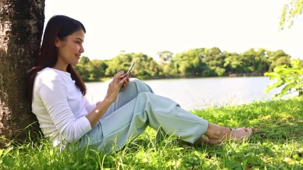 Piękna Długowłosa Azjatka Siedzi Cieszy Się Swoim Smartfonem Ogrodzie Botanicznym — Wideo stockowe