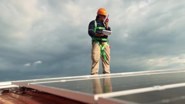 亚洲男性电气工程师检查钢制屋面工厂安装太阳能电池板的情况 环行屋面区域 举行电钻检查每个太阳能电池板的重要位置 — 图库视频影像