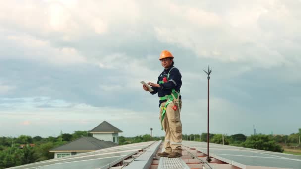 小组工程师通过无线电用平板通讯检查安装在高屋顶可再生能源技术进料厂上的太阳能电池板的安装情况 — 图库视频影像