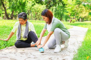 Yaşlı bir kadın, bileğini burktuğu için kızından ilk yardım alarak bahçede spor yaparken sol ayak bileğinde zemin ağrısı çekiyor:.