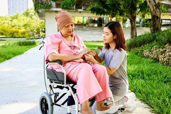 Daughter sits holding the hand of her elderly mother who is sick with cancer and is being treated in the hospital. The daughter\'s gratitude for being attached mother supports her in hopes of recovery.