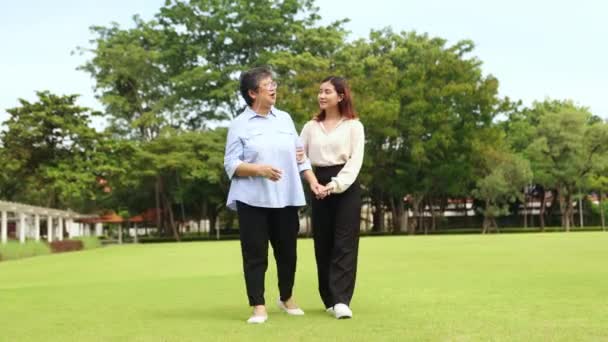 母亲和女儿在美好的气氛中成长 快乐的散步在花园草坪上表达爱意 拥抱在一起照顾老年人的健康 加强家庭关系 — 图库视频影像