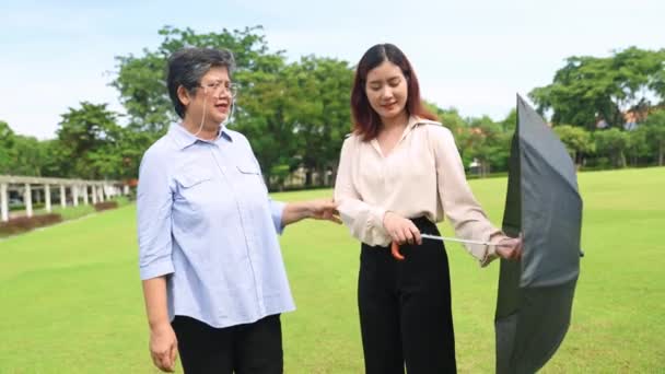 Anciana Madre Hermosa Hija Asiática Caminan Juntas Jardín Sosteniendo Sombra — Vídeo de stock