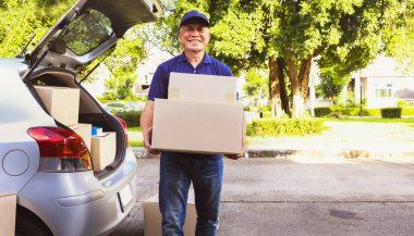 Ev teslimatı: Son sınıf erkek çalışanı kamyonun arkasında duruyor, müşterinin paket teslimat listesini ve karton kutu ürünlerini doğru teslimat için bir panoya kaydediyor..