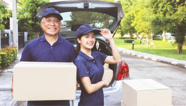 Teslimat işi eve servis işi: Emekli erkek ve kadın teslimat şoförü, ellerinde tebessümle bekleyen kutularla ayakta duruyorlar müşteriler siparişlerini alıyorlar.