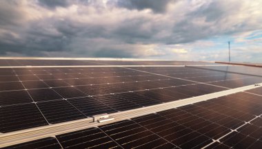 Endüstriyel bir fabrikanın eğimli çatısına enerji depolama maliyetinden tasarruf etmek ve doğal enerjinin sürdürülebilir kullanımı için modern teknolojinin güneş panelleri kurulumu resmi.