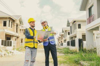 Baş müteahhit işçi erkek ressamla ev danışmanlığı tasarlayan mimar, iç ve dış boyama çalışmaları için renk broşürleri tutuyor. Renk eşleşmesi özelliklerini tasarıma göre seçiyor..