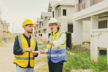 Baş müteahhit işçi erkek ressamla ev danışmanlığı tasarlayan mimar, iç ve dış boyama çalışmaları için renk broşürleri tutuyor. Renk eşleşmesi özelliklerini tasarıma göre seçiyor..