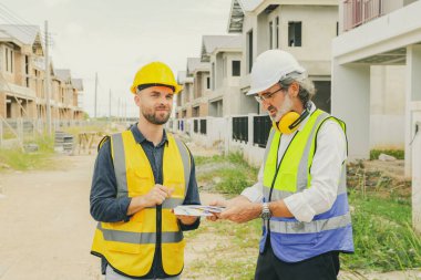 Baş müteahhit işçi erkek ressamla ev danışmanlığı tasarlayan mimar, iç ve dış boyama çalışmaları için renk broşürleri tutuyor. Renk eşleşmesi özelliklerini tasarıma göre seçiyor..