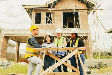 Çok ırklı erkek ve kadın mimarlarla toplantı ekibi inşaat mühendisleri ve erkek güvenlik görevlileri, iskan inşaatı projesinde çalışan ve yönetmeliğe uyan işçileri denetliyor..