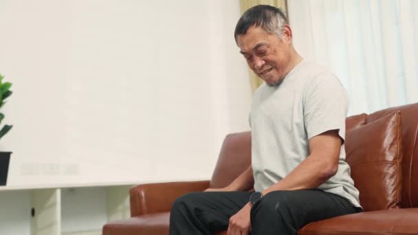 亚洲一位患有心脏病的老人坐在沙发上玩手机 测量心跳时 突然感到心脏肌肉酸痛和疲倦 — 图库视频影像