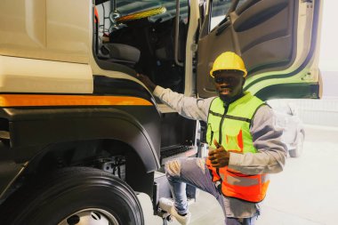 Afrika kökenli Amerikalı işçi çelik römork kullanıyor. Emniyet kemerlerinin durumunu kontrol ediyor. Güvenlik materyalleri hazır mal teslimatı ve kazaları önlemek için seyahat etmeden önce onay veriyor..