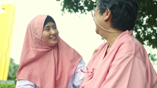 女性穆斯林志愿者在医院花园友好地坐着与老年患者交谈 为他们提供鼓励 祝他们健康 快速康复 并照顾他们的健康 — 图库视频影像