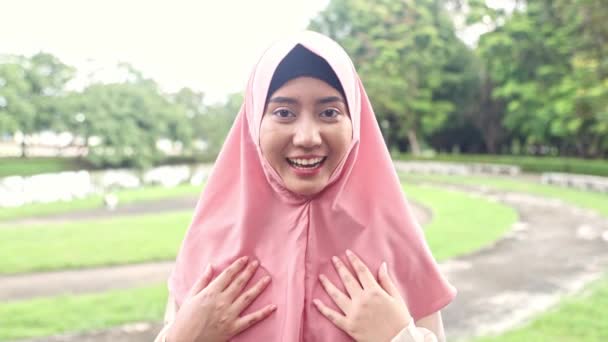 快乐的形象可爱的亚洲穆斯林女人 头戴头巾站在那里 双手高举 友好地看着相机 给人迷人的微笑 向你打招呼或致谢 — 图库视频影像