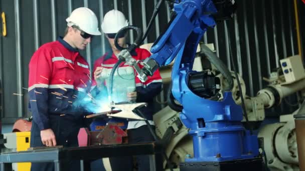 戴防护护目镜的小组机械工程师操作焊接机器人臂测试现代钢板电焊和工业技术控制遥控系统专家技术员 — 图库视频影像