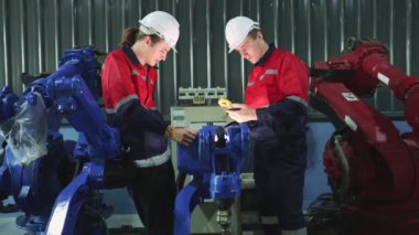Ekip erkek mühendis teknisyenleri güvenlik için robot kolunun sıkılığını kontrol ediyor. Elektrik kaynaklama bakımı ve çoklu-metre kontrol sistemi manevra kabiliyeti kullanıyor..