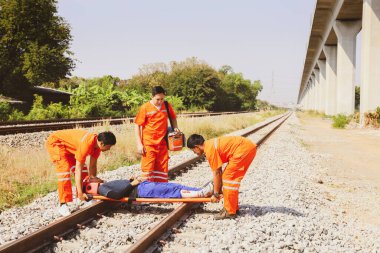 Kurtarma görevlisi gönüllü personel, saha gergisini ve ilk yardım ekipmanlarını hazırlayın. Demiryolunda bir trenin çarptığı ağır yaralı kişinin nakline yardım edin. Dikkatlice hastaneye git.