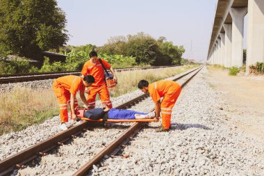 Kurtarma görevlisi gönüllü personel, saha gergisini ve ilk yardım ekipmanlarını hazırlayın. Demiryolunda bir trenin çarptığı ağır yaralı kişinin nakline yardım edin. Dikkatlice hastaneye git.