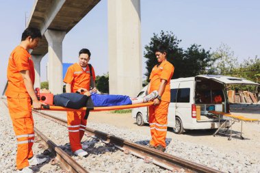 Kurtarma görevlisi gönüllü personel, saha gergisini ve ilk yardım ekipmanlarını hazırlayın. Demiryolunda bir trenin çarptığı ağır yaralı kişinin nakline yardım edin. Dikkatlice hastaneye git.