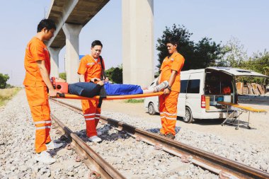 Kurtarma görevlisi gönüllü personel, saha gergisini ve ilk yardım ekipmanlarını hazırlayın. Demiryolunda bir trenin çarptığı ağır yaralı kişinin nakline yardım edin. Dikkatlice hastaneye git.