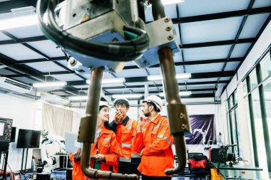 Robot Geliştirme Enstitüsü 'nde çalışan erkek ve kadın robot mühendislik öğrencileri uzaktan kumandalı robot makineleri kullanan modern endüstrileri destekleyen robot silah operasyonunu araştırıyor ve araştırıyorlar..